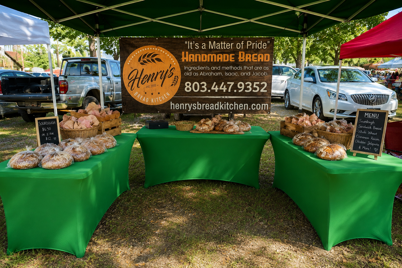 Henry's Bread Kitchen full booth setup at a Saturday farmers market, three tables of bread with a hand-painted banner.